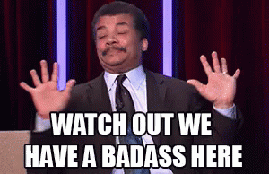 a man in a suit and tie is making a funny face and says watch out we have a badass here .