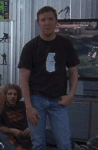 a man in a black shirt stands in front of a sign that says don 't be mad at us