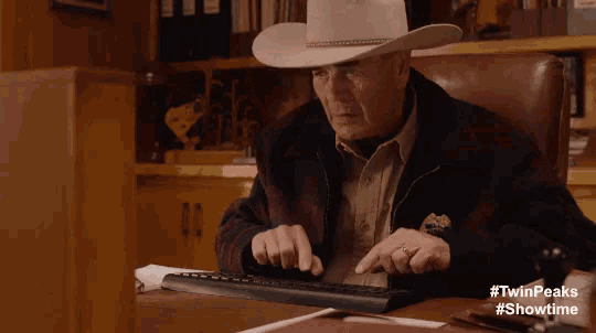 a man in a cowboy hat typing on a keyboard a man in a cowboy hat typing on a keyboard